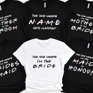 May include: Six black and white t-shirts with the text "The One Where I'm The" and a different role related to a wedding, such as "Bride", "Maid of Honor", "Mother of the Bride", and "Groom".
