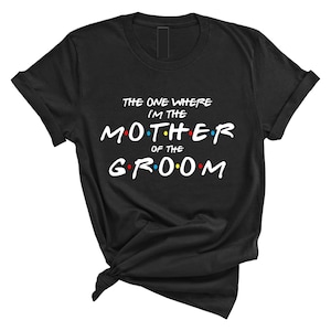 May include: Black t-shirt with white text that reads "The One Where I'm The Mother Of The Groom" in a font reminiscent of the popular TV show "Friends".