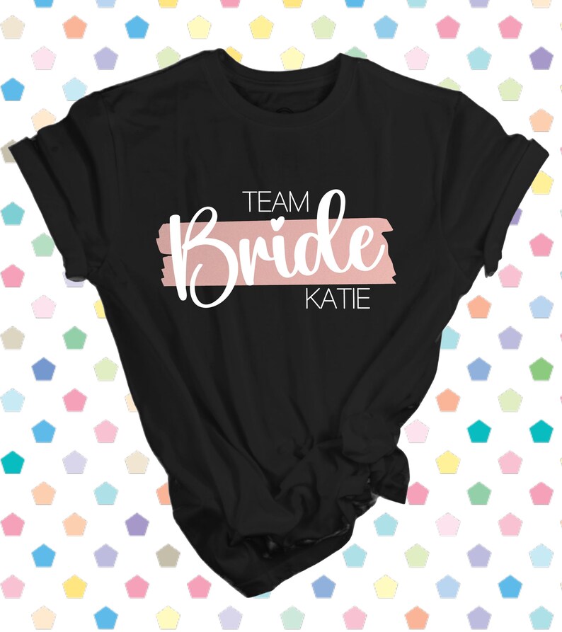 May include: Black t-shirt with a pink stripe and the text "Team Bride Katie" in white.