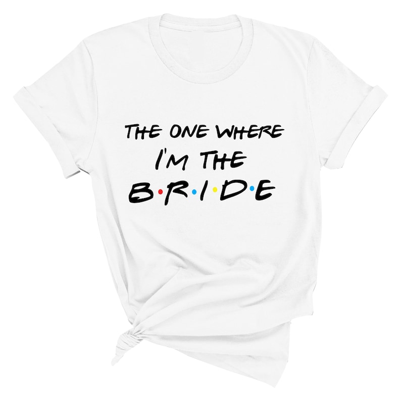 May include: White t-shirt with black text that reads "The One Where I'm The B.R.I.D.E." with colorful dots between the letters.