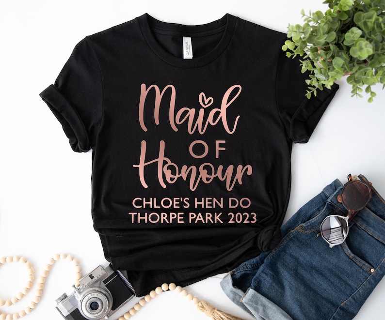 May include: Black t-shirt with rose gold text that reads "Maid of Honour Chloe's Hen Do Thorpe Park 2023".