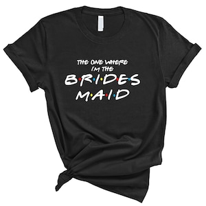May include: Black t-shirt with the text "The One Where I'm The Bridesmaid" in white with colorful dots.