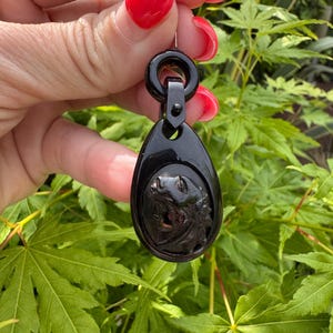 May include: A black jet pendant with a carved animal design. The pendant has a loop at the top for attaching to a chain or cord.
