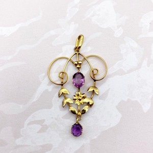 May include: A gold pendant with a delicate floral design and three purple amethyst stones.