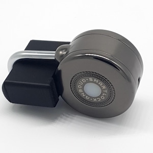 Pode incluir: Um cadeado preto e prateado com uma face de fechadura redonda prateada que diz "GANLOCK SMARTLOUD".