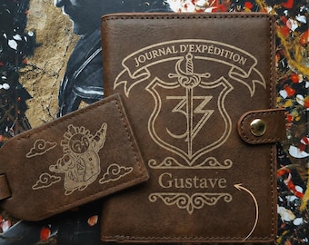 May include: Brown leather passport holder and luggage tag set. The passport holder features the text "JOURNAL D'EXPÉDITION" and "Gustave". The luggage tag has an illustration of a character with clouds. The text "Customize with a name or nickname" is also visible.