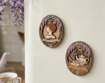 May include: Two wooden oval magnets with a vintage theme are attached to a white surface. One magnet features a profile of a woman and the text "Dearest Gentle Reader." The other magnet shows a teapot and teacup with the text "Tea Time."
