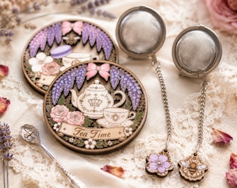 May include: Two circular wooden coasters featuring intricate illustrations of teapots, cups, and purple floral accents with the text Tea Time, accompanied by two metal mesh tea infusers with decorative wooden charms and a small silver spoon with a bee motif.