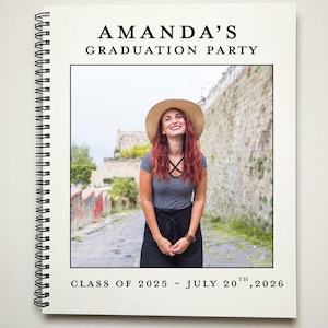 May include: A white graduation party announcement with black text. The text reads "Amanda's Graduation Party" and "Class of 2025 - July 20th, 2026". A photo of a woman wearing a straw hat and a striped shirt is in the center of the announcement.