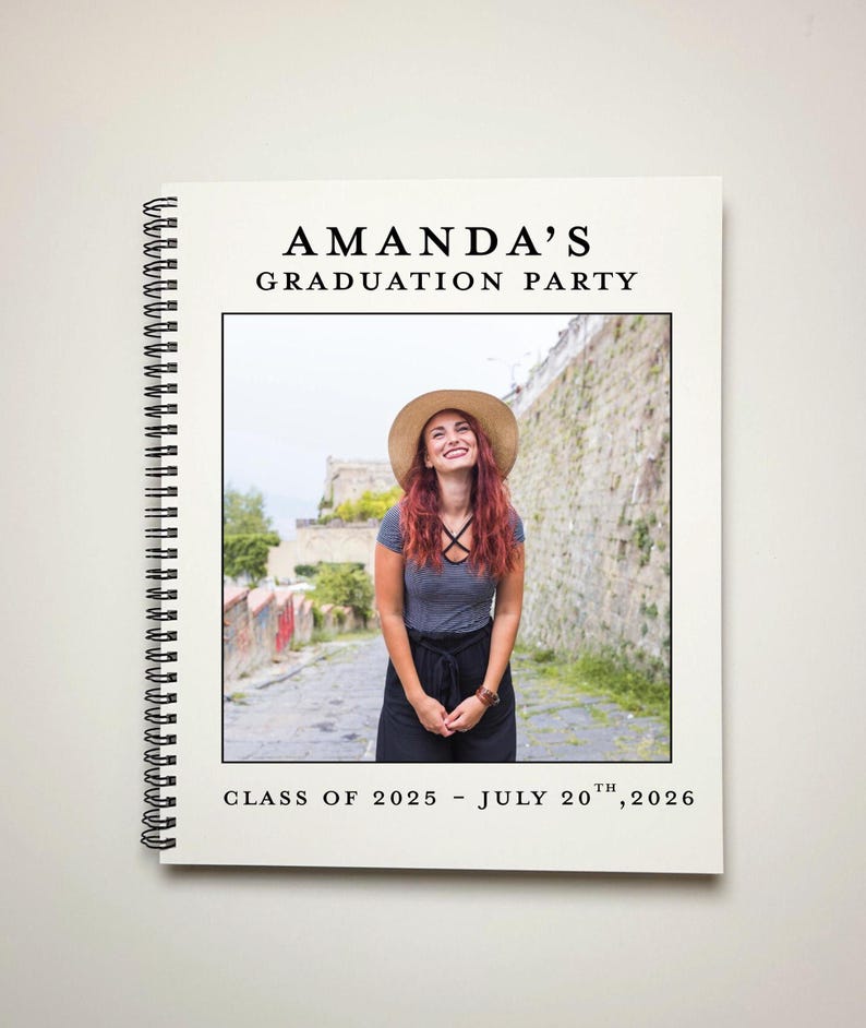 May include: A white graduation party invitation with a black border. The invitation has a photo of a woman wearing a hat and smiling. The text on the invitation reads "Amanda's Graduation Party, Class of 2025 - July 20th, 2026".