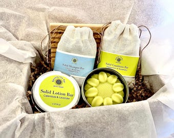 Puede incluir: Una caja de regalo llena de productos naturales para el baño y el cuerpo. La caja contiene una barra de loción sólida en una lata, una barra de champú sólida en una bolsa de muselina blanca y una barra de acondicionador sólida en una bolsa de muselina blanca. Los productos están etiquetados con el nombre de la marca "Raising the Bar with Hemp".