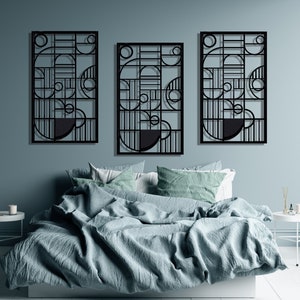 May include: Three black metal wall sculptures with geometric designs, featuring circles and lines, hanging above a bed with blue bedding.