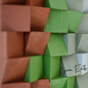 May include: Abstract wall art made of wood blocks painted in shades of green, brown, and gray. The blocks are arranged in a geometric pattern, creating a modern and minimalist design. The text "Green Earth" is visible in the lower right corner of the image.