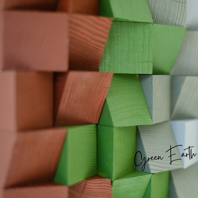 May include: Abstract wall art made of wood blocks painted in shades of green, brown, and gray. The blocks are arranged in a geometric pattern, creating a modern and minimalist design. The text "Green Earth" is visible in the lower right corner of the image.