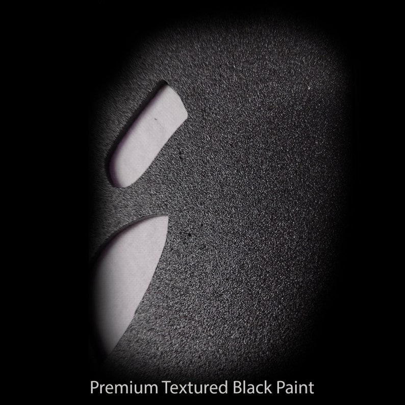 May include: Close-up of a textured black surface with two white shapes cut out. The surface has a fine, grainy texture.  Premium Textured Black Paint.