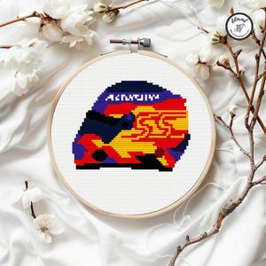 May include: A cross-stitch design in a wooden embroidery hoop. The design features a colorful, pixelated image with the text "ARIZONA" in white. The design incorporates red, yellow, blue, and black colors.