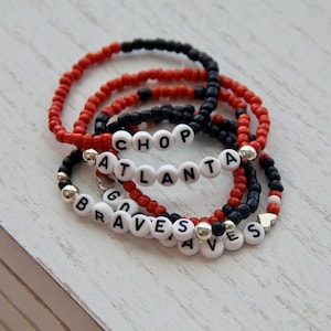 May include: A set of red and black beaded bracelets with white letter beads spelling out "CHOP", "ATLANTA", "GO", and "BRAVES".