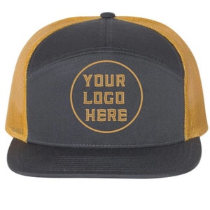 Könnte beinhalten: Eine schwarze und goldene Trucker-Kappe mit Netzrücken. Die Vorderseite der Kappe hat einen Kreis mit dem Text "YOUR LOGO HERE" in Gold.