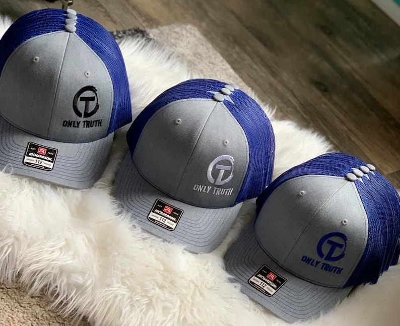 May include: Three gray and blue trucker hats with a white embroidered logo that says "ONLY TRUTH" and a white circle with a letter "T" inside the circle.