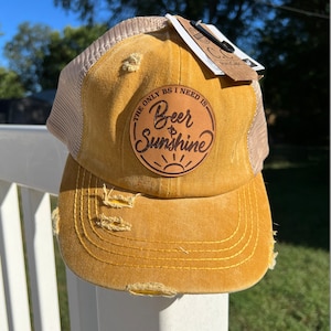 May include: A yellow distressed baseball cap with a brown patch that says "The only BS I need is Beer & Sunshine".