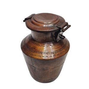 Può includere: Un contenitore in rame vintage con un coperchio incernierato. Il contenitore presenta un design in rilievo intricato e una patina marrone scuro.