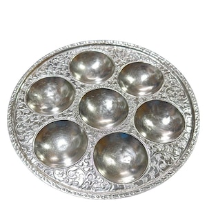 May include: A silver Seder plate with six individual bowls for holding the traditional Passover foods. The plate has an ornate, embossed design.