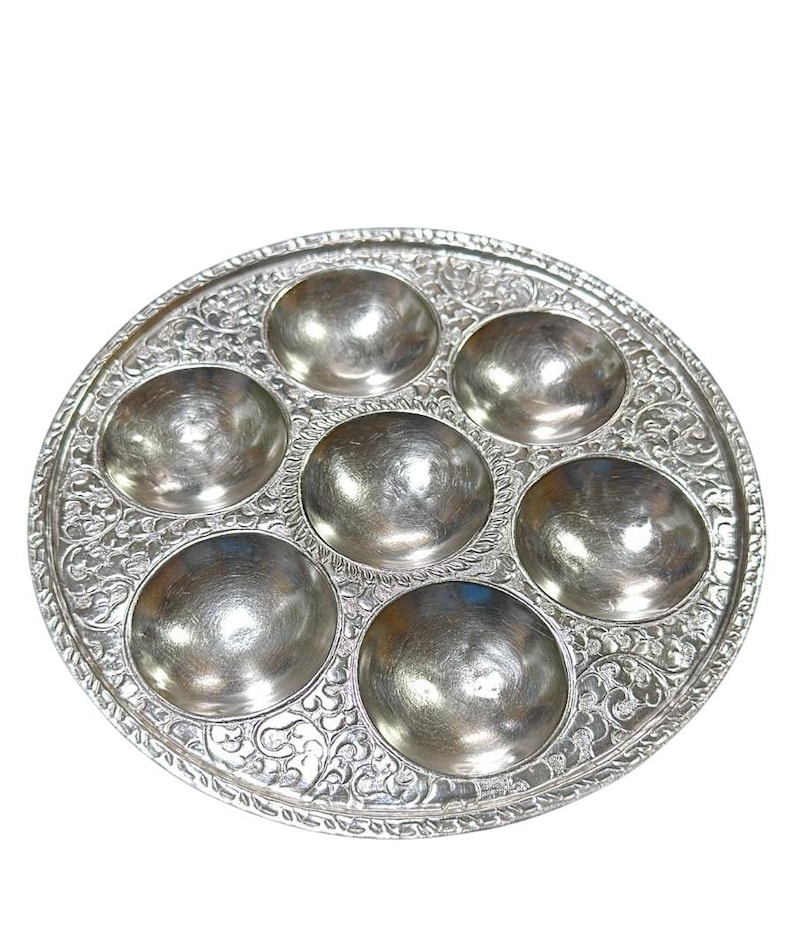 May include: A silver Seder plate with six individual bowls for holding the traditional Passover foods. The plate has an ornate, embossed design.