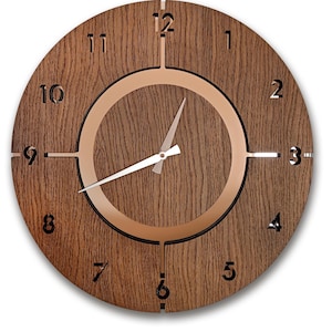 May include: A round wooden wall clock with a dark brown wood grain finish. The clock features a copper-colored ring around the center and black numerals. The hands are white. The clock measures approximately 12 inches in diameter.