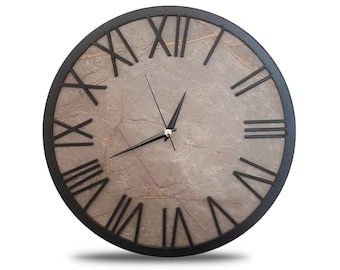 May include: A black framed clock with Roman numeral markings on a beige marble-like background.