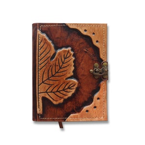 May include: A brown leather journal with a tooled leaf design and a brass clasp. The journal has a stitched edge and a brown leather strap.