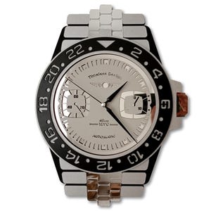 May include: A silver-coloured watch with a black bezel and a silver band. The watch face has two sub-dials and the text "Timeless Design" and "Swiss 1890 Automatic". The watch hands are black.