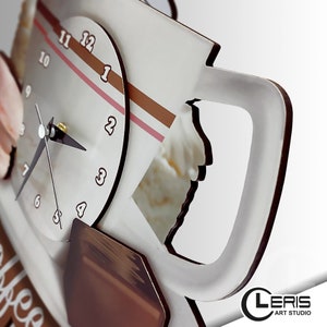 May include: A white coffee mug clock with brown and pink stripes. The clock face has black numbers and hands. The mug has a brown handle and a white background with a brown and pink stripe design. The clock is shaped like a coffee mug and has the word "Coffee" written on the bottom.