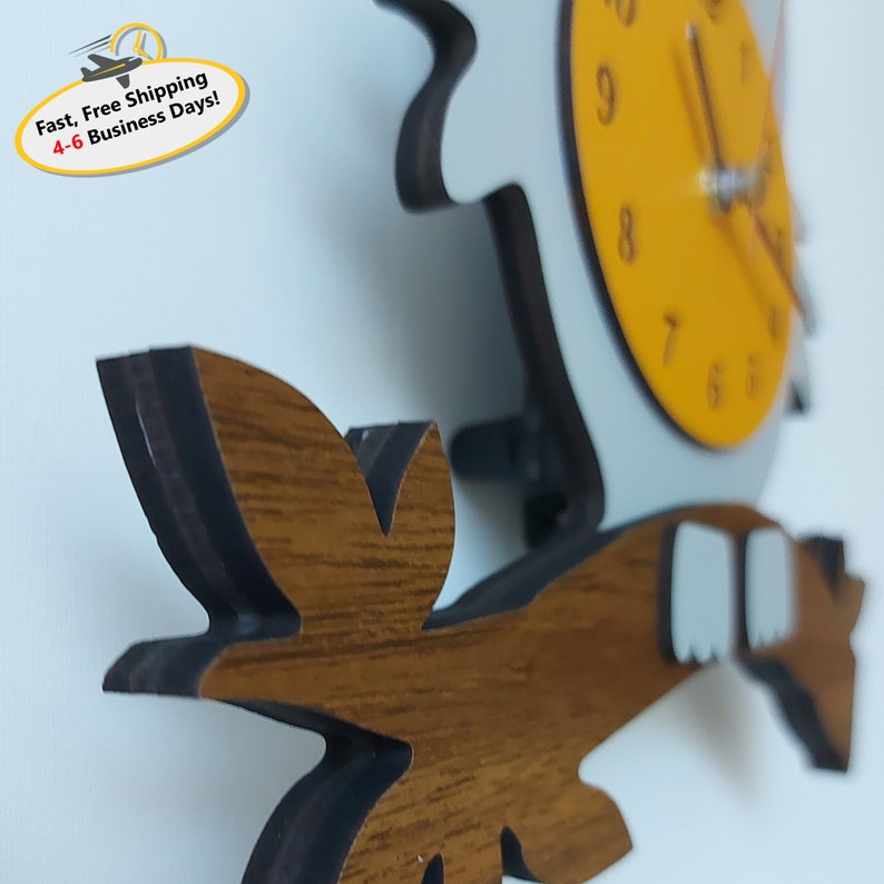 May include: A wooden owl clock with a yellow face and black hands. The owl is perched on a brown branch with green leaves. The clock is a unique and whimsical addition to any home.
