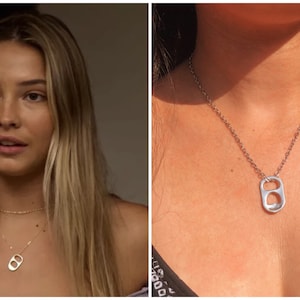 May include: A silver necklace with a pull tab pendant. The pendant is shaped like a can tab with a hole in the center. The necklace is worn by a person with long blonde hair.
