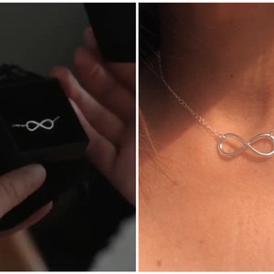 May include: A silver infinity ring in a black velvet box and a silver infinity necklace on a person's neck.