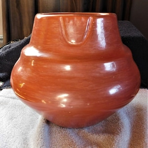 Puede incluir: Un jarrón de cerámica grande, rojo, hecho a mano, con una forma redondeada única y un acabado liso y brillante.