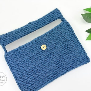 May include: A blue crocheted laptop sleeve with a wooden button closure. The sleeve is open and a laptop is inside.