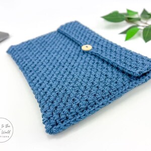 May include: A blue crocheted envelope clutch with a wooden button closure. The clutch is made with a textured stitch and is ideal for carrying small items.