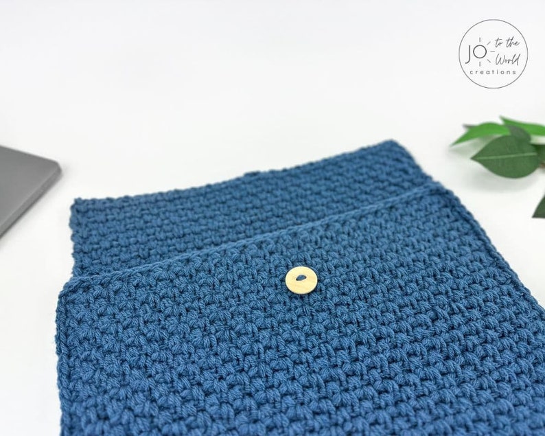 May include: A blue crocheted laptop sleeve with a wooden button closure.