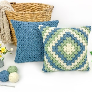 May include: Two square crochet pillows. One is solid blue with a textured stitch pattern. The other features a multi-colored granny square design in blue, sage green, and cream. A logo with the text Jo to the World Creations is visible.