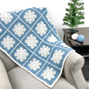 May include: A blue and white crocheted blanket with a snowflake pattern. The blanket is draped over a gray armchair. The blanket is approximately 40 inches wide and 50 inches long.