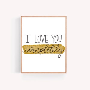 May include: A printable wall art print with a gold watercolor background and the text "I love you completely" in black.