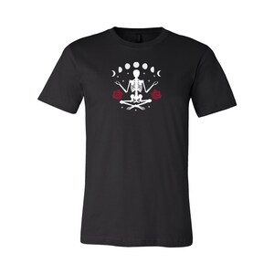 May include: Black t-shirt with a white skeleton meditating with a crescent moon and stars above and red roses on either side.