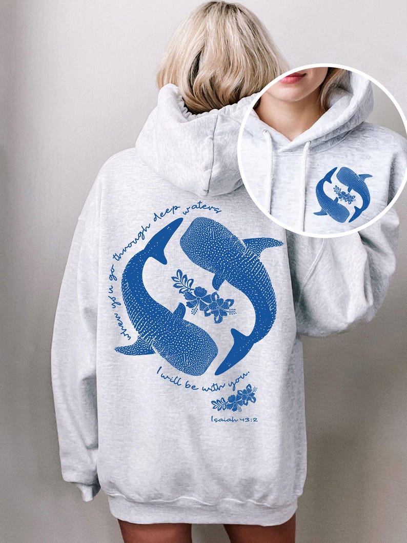 K&ouml;nnte beinhalten: Ein hellgrauer Kapuzenpullover mit blauem Aufdruck auf der R&uuml;ckseite und Vorderseite. Das R&uuml;ckendesign zeigt zwei Walhaie, florale Akzente und den Text: When you go through deep waters, I will be with you. Isaiah 43:2. Die Vorderseite hat ein kleineres, passendes Walhai-Motiv.