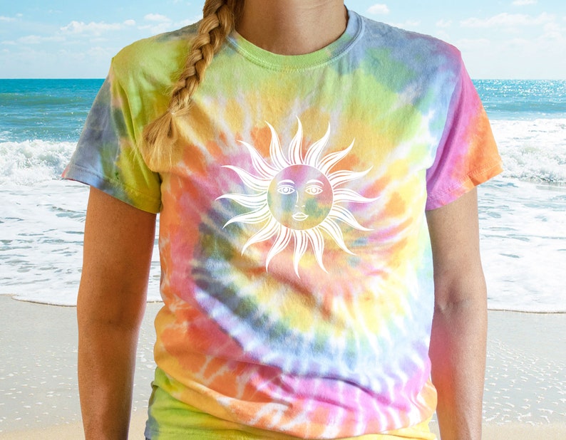 May include: A tie-dye t-shirt with a vibrant rainbow pattern of yellow, green, orange, and pink. The shirt features a white sun graphic with a face. The short-sleeved tee is a casual, colorful garment.