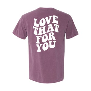 K&ouml;nnte beinhalten: Ein lila T-Shirt mit dem Text "LOVE THAT FOR YOU" in wei&szlig;er Schrift im Retro-Stil.