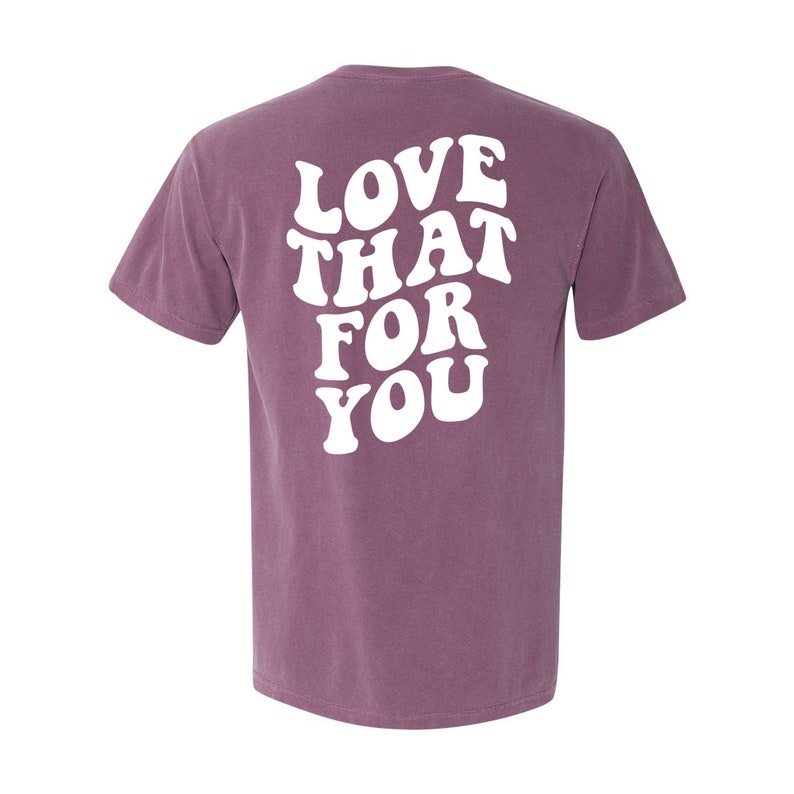 K&ouml;nnte beinhalten: Ein lila T-Shirt mit dem Text "LOVE THAT FOR YOU" in wei&szlig;er Schrift im Retro-Stil.