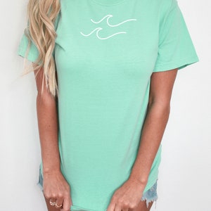May include: A light green t-shirt with a white wave design and the text "Island Reef" printed on the bottom.