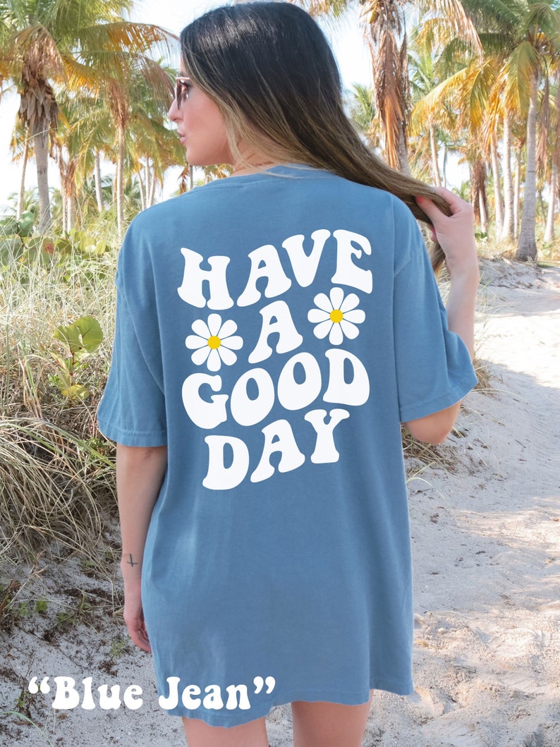 May include: A blue jean t-shirt with the text "HAVE A GOOD DAY" in white with daisy flowers.