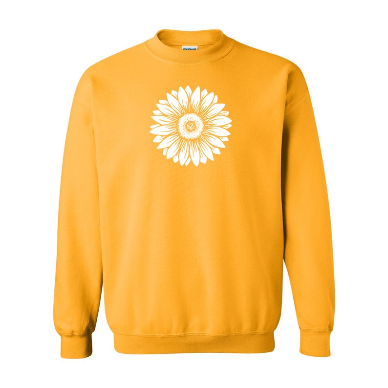 Pu&ograve; includere: Una felpa gialla con una grafica di girasole bianca sul davanti.